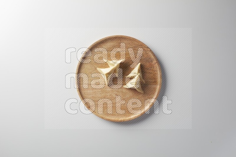 Four Sambosas on a wooden round plate on a white background