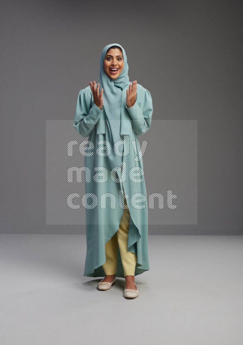 Saudi Woman wearing Abaya standing interacting with the camera on Gray background