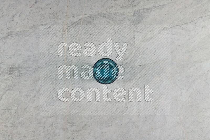 A turquoise glass cup on grey marble background