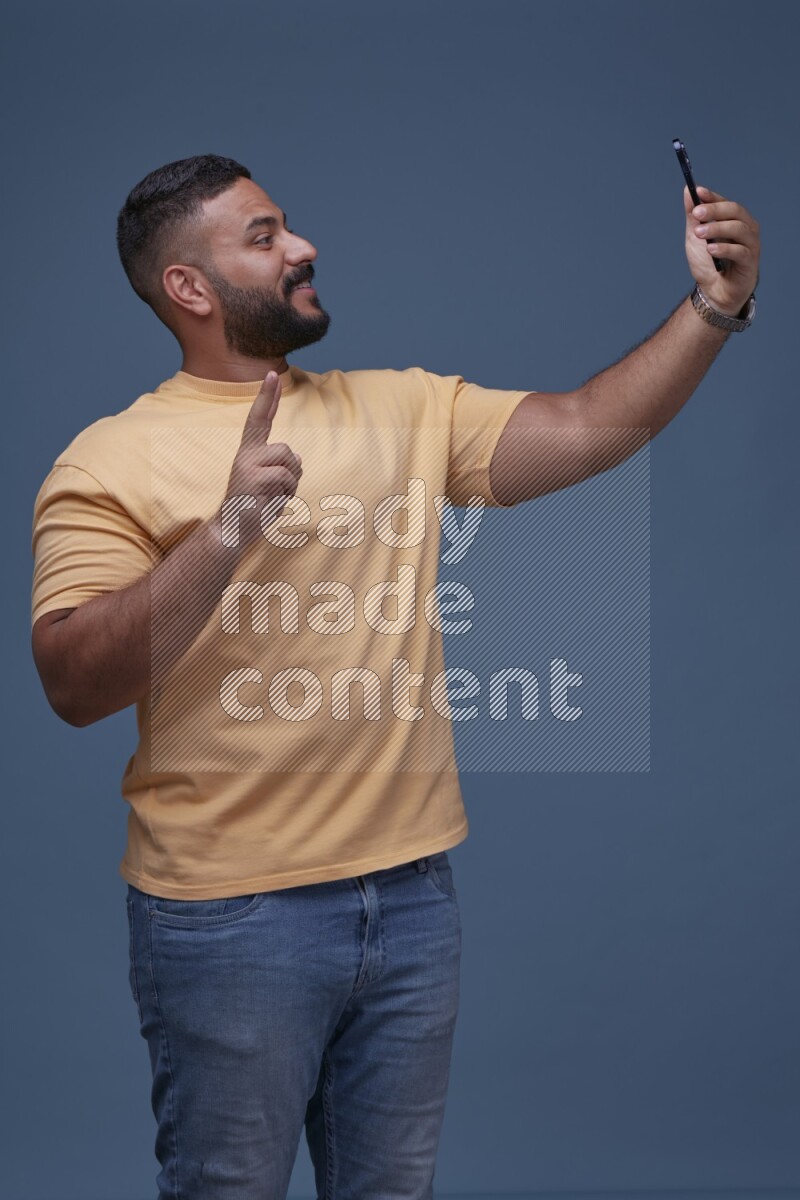 A man Taking A Selfie on Blue Background wearing Orange T-shirt