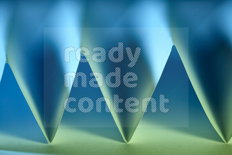 صورة مجردة مقربة تظهر طيات ورقية هندسية حادة بتدرجات اللون الأخضر والأزرق