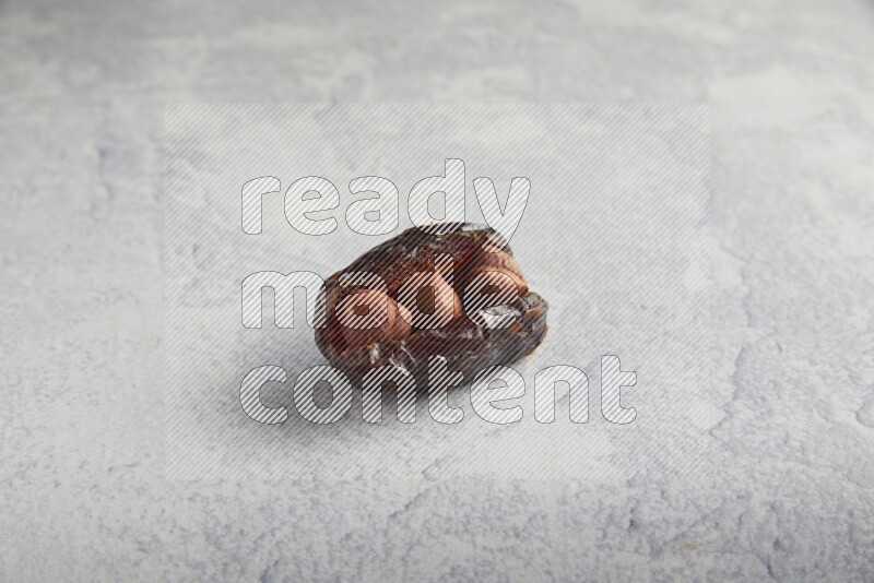 hazelnuts stuffed madjoul date on a light grey background