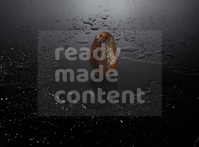 A whole avocado on black background with water drops.