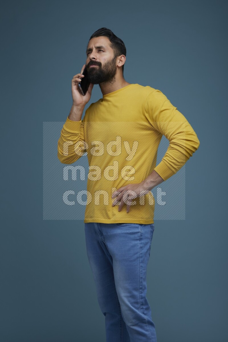 A man having a calling in a blue background wearing a yellow shirt