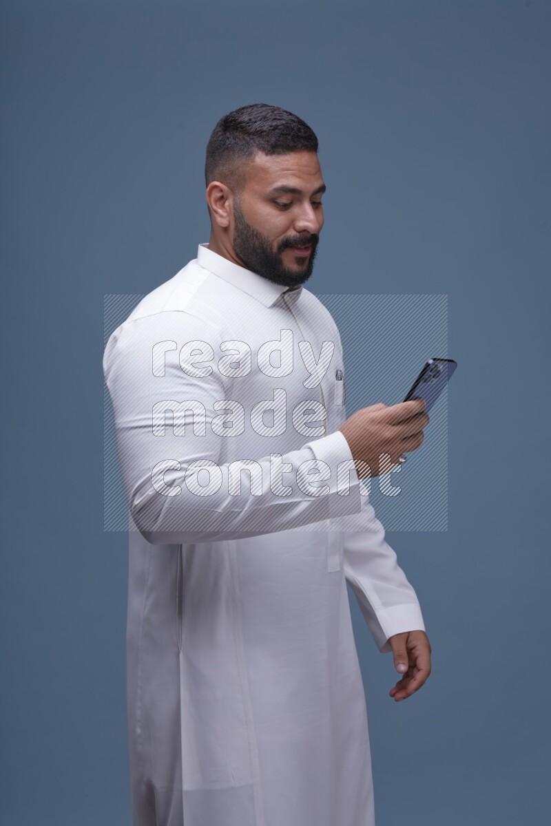 A man Texting on Blue Background wearing Saudi Thob