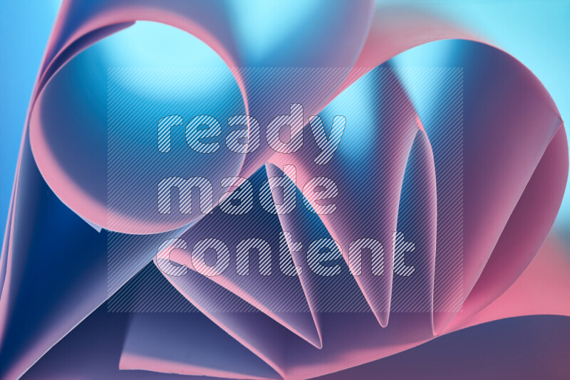 An artistic display of paper folds creating a harmonious blend of geometric shapes, highlighted by soft lighting in blue and pink tones
