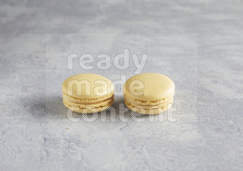 45º Shot of two Yellow Vanilla macarons  on white  marble background