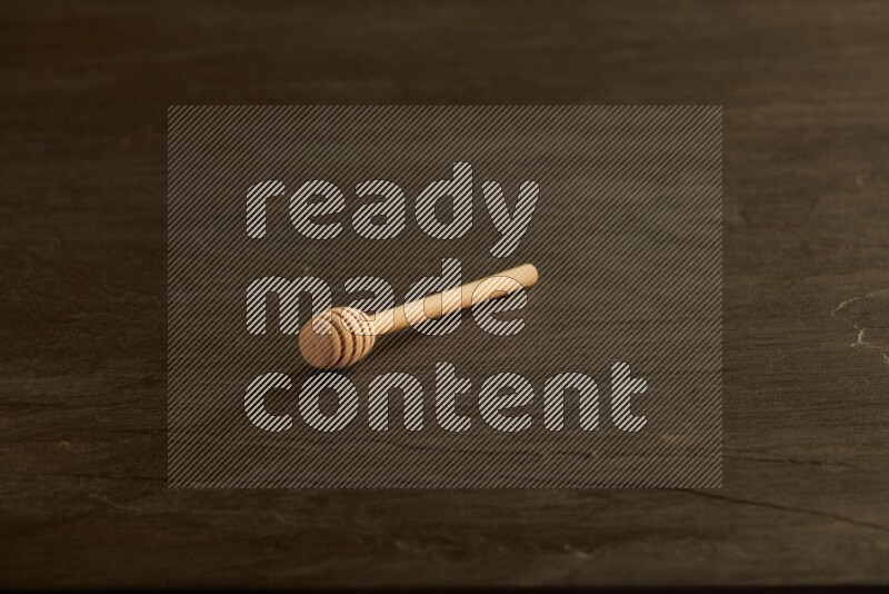 Wooden honey dipper on black slate background