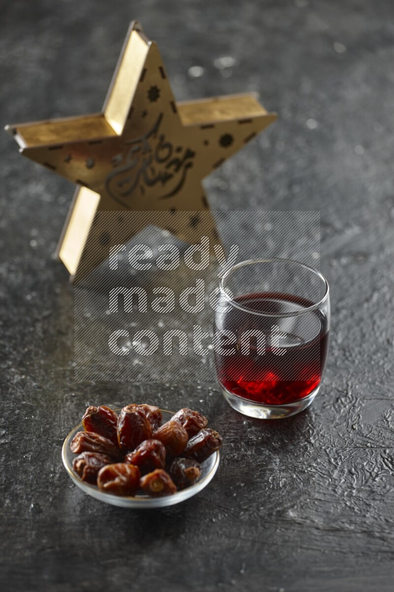 A wooden golden star lantern with different drinks, dates, nuts, prayer beads and quran on textured black background
