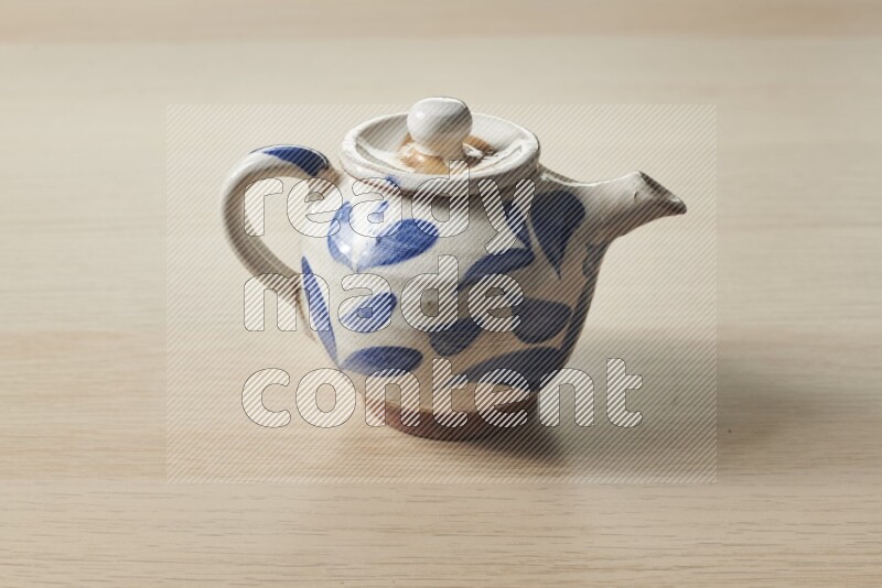 A pottery teapot on light wooden background