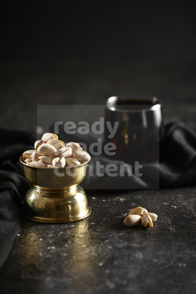 Nuts in a metal bowl with tamarind and a napkin in a dark setup