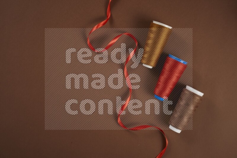 A red collection of sewing and tailoring tools arranged on a brown background