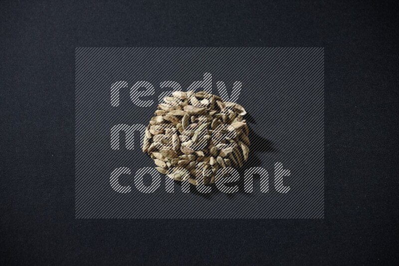 Cardamom in a circle shape on black flooring