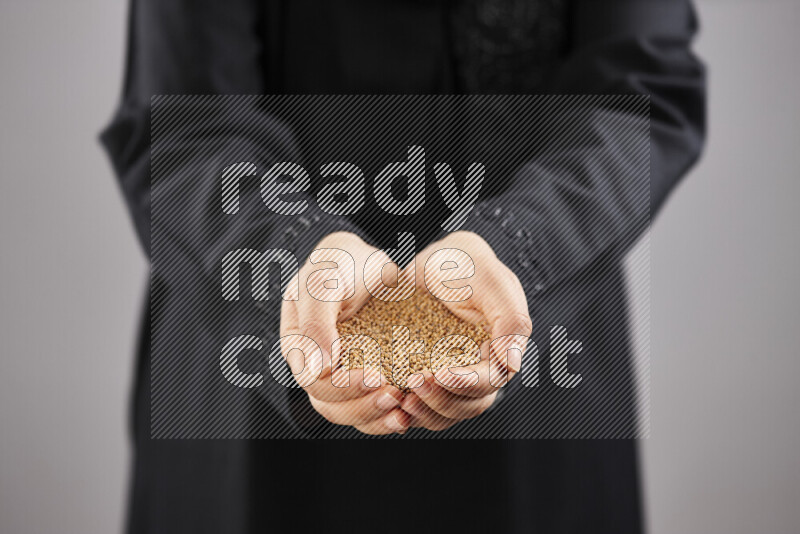 Woman in abaya holding different kinds of spices in different positions