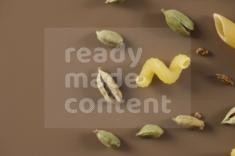 معكرونة مع مكونات متنوعة من الطماطم والثوم والبصل والفلفل الأحمر والفلفل الأسود والفلفل الأبيض وأوراق الغار وإكليل الجبل والهيل على خلفية بيج