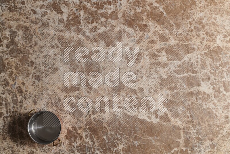 A small copper pot on beige marble background
