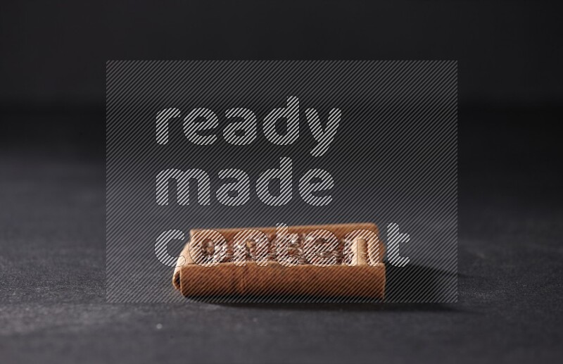 A single square of cinnamon sticks full of flaxseeds on black flooring