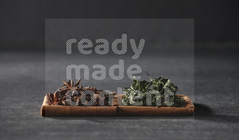 مربعان من أعواد القرفة ممتلئان باليانسون النجمي والنعناع المجفف علي خلفية سوداء