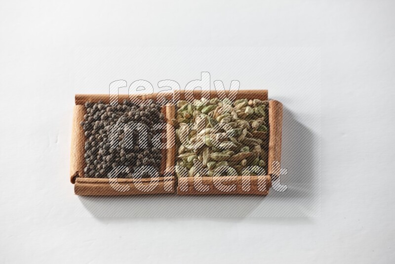 2 squares of cinnamon sticks full of cardamom and black pepper on white flooring