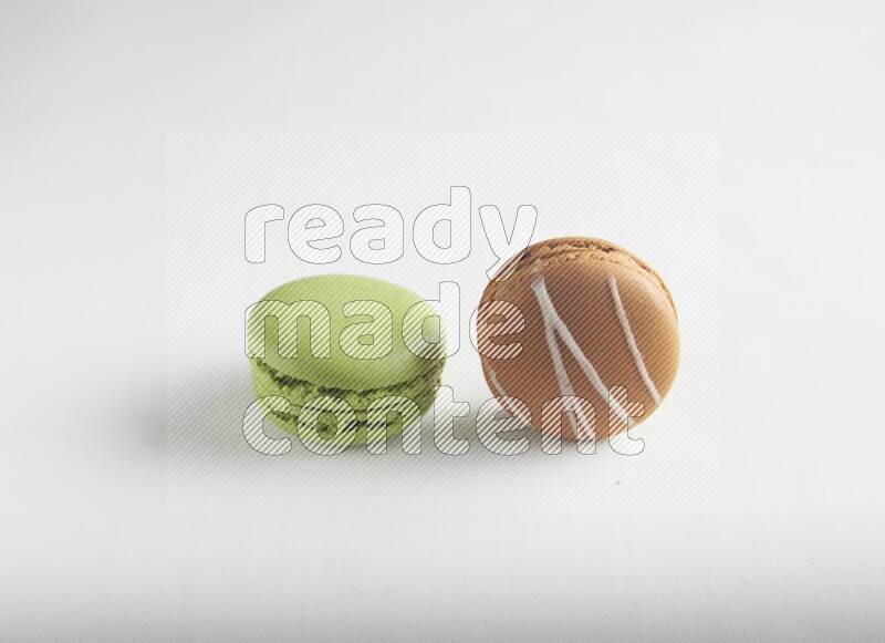 45º Shot of of two assorted Brown Irish Cream, and Green Pistachio macarons on white background
