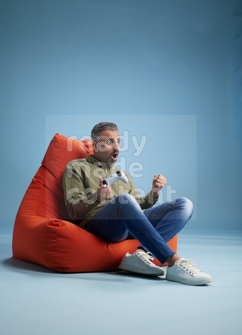A man sitting on an orange beanbag and gaming with joystick