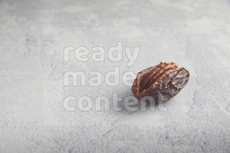 pecan stuffed madjoul date on a light grey background