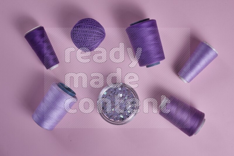 A purple and pink collection of sewing and tailoring tools arranged on a pink background