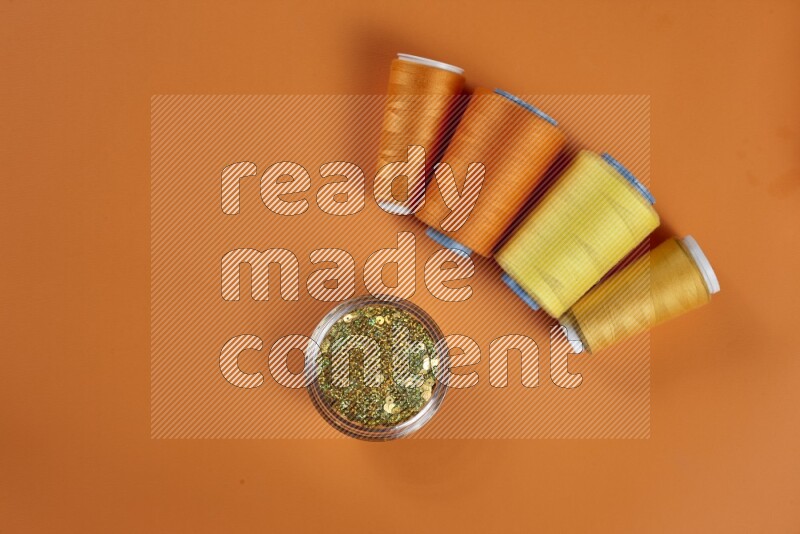 A yellow collection of sewing and tailoring tools arranged on a orange background