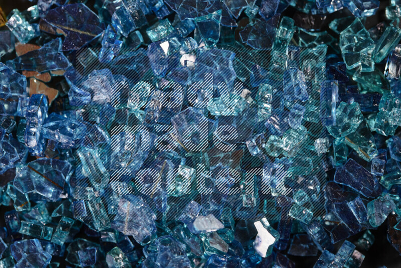 Transparent blue fragments of glass scattered on a black background