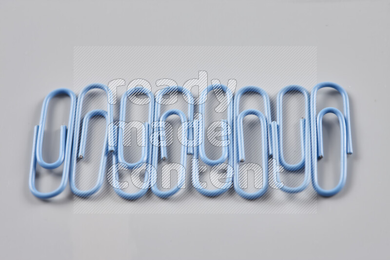 Blue paper clips isolated on a grey background