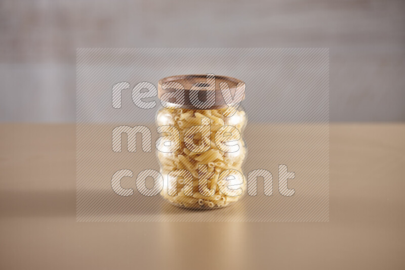 Raw pasta in glass jars on beige background