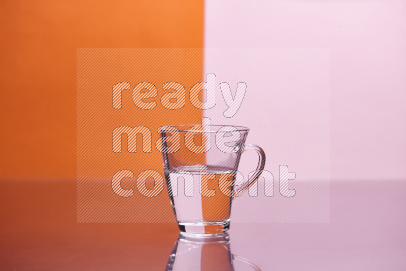 The image features a clear glassware filled with water, set against orange and rose background