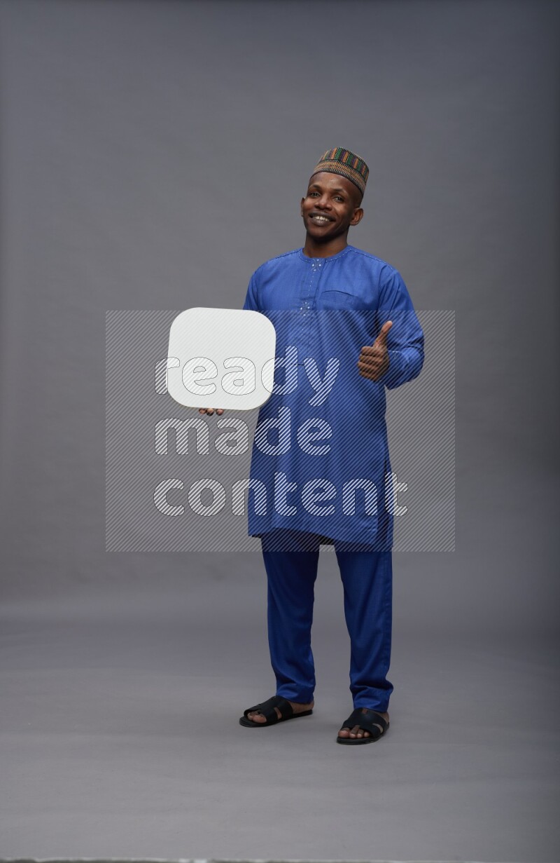 Man wearing Nigerian outfit standing holding social media sign on gray background