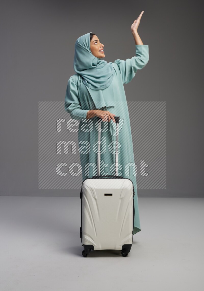 Saudi Woman wearing Abaya standing holding Travel bag on Gray background