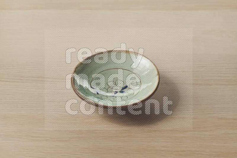 A decorative pottery plate on light wooden background