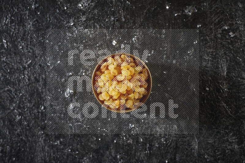 Dried fruits in a metal bowl in a dark setup