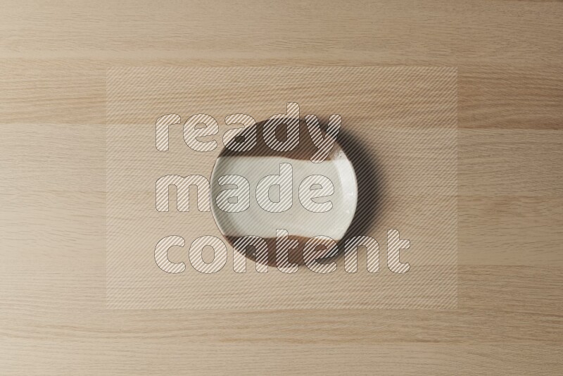 A multicolored pottery plate on light wooden background