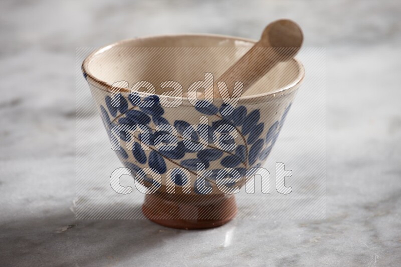 Decorative pottery bowl with wooden honey dipper in it on grey marble background