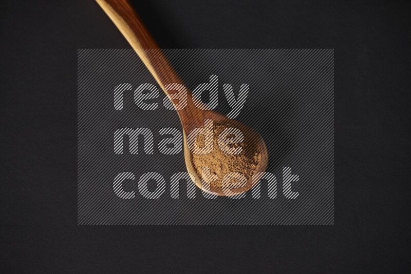 Cinnamon powder in a wooden ladle spoon on black background in different angles