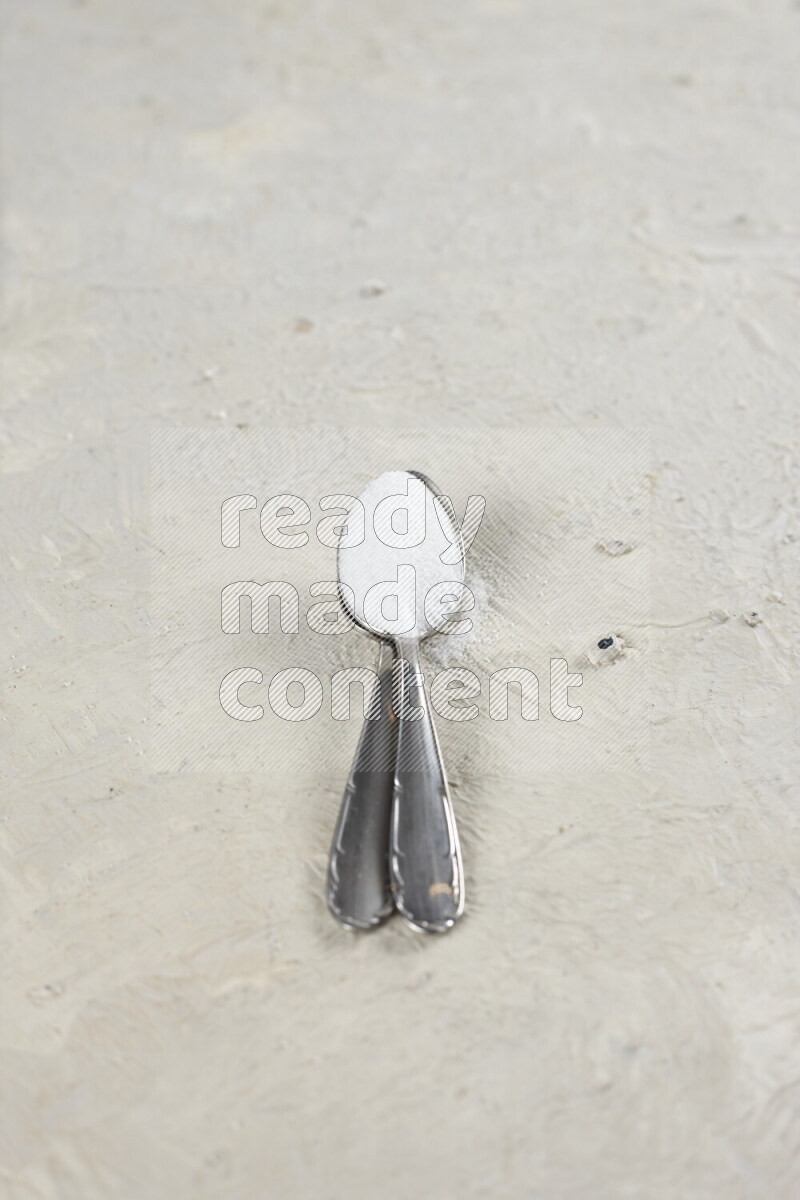 2 metal spoons filled with fine table salt and fine pink himalayan salt on white background