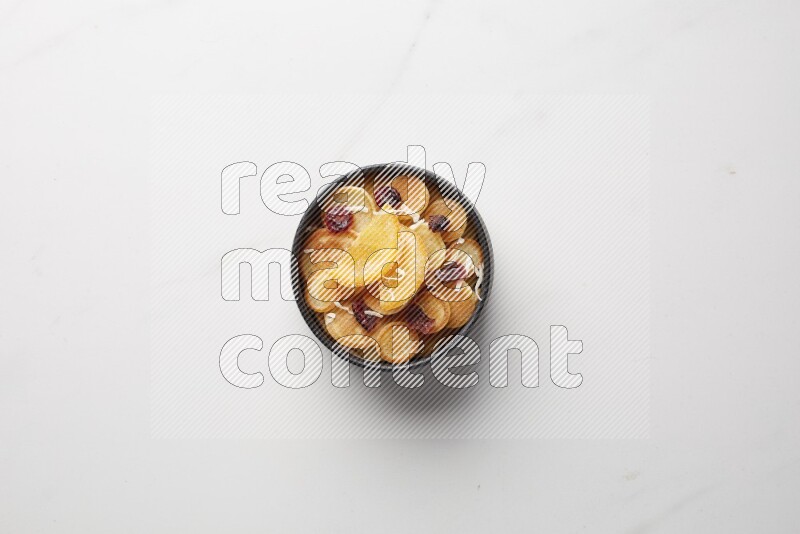 Top-view shot of orange candy cereal pancakes in a round bowl on white background