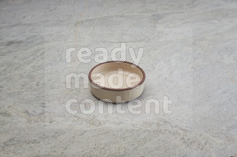 A beige pottery oven bowl on grey marble background