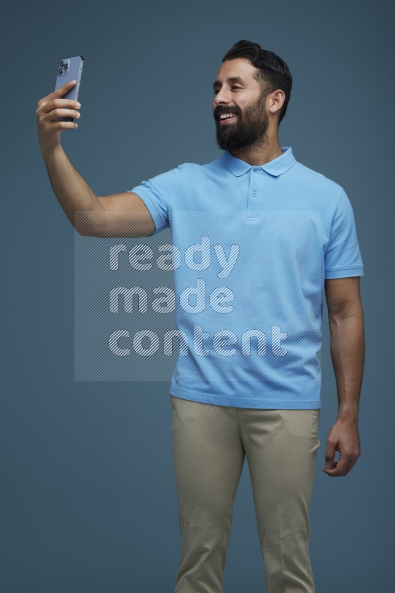 Man Taking a Selfie in a blue background wearing a Blue shirt
