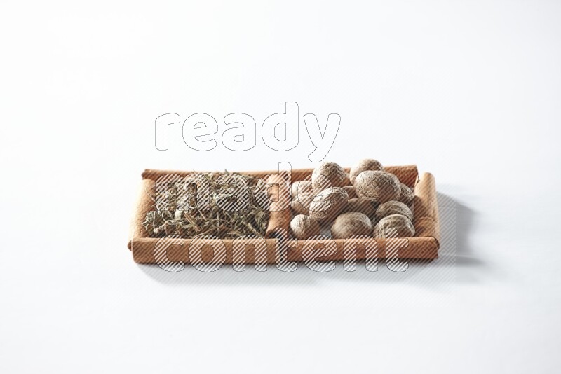 2 squares of cinnamon sticks full of dried basil and nutmegs on white flooring