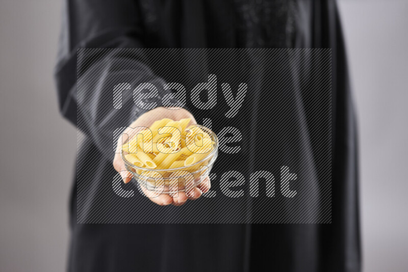 Woman in abaya holding different kinds of pasta in different positions
