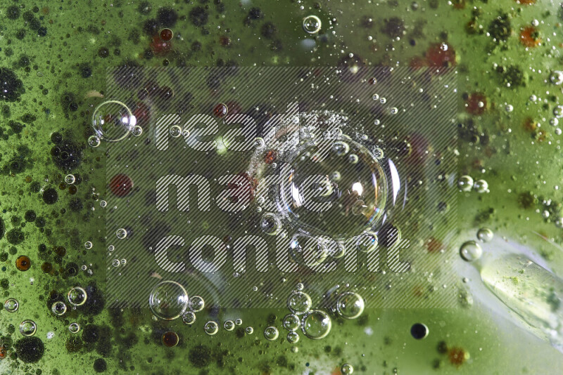 Close-ups of abstract red, green and blue watercolor drops on oil Surface on green background
