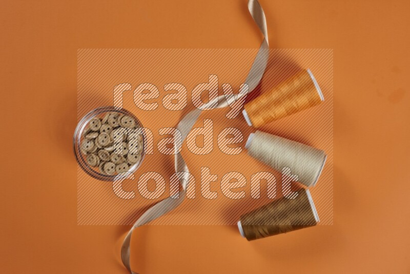 A brown collection of sewing and tailoring tools arranged on a orange background