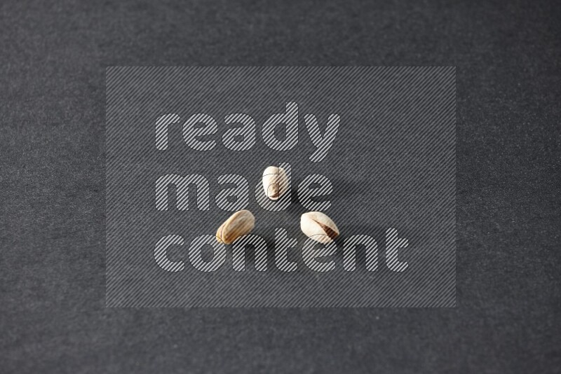 3 pistachios on a black background in different angles