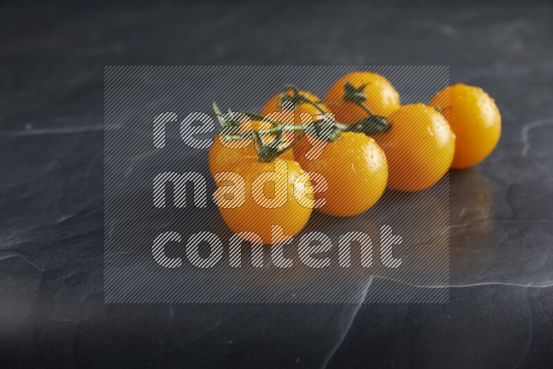 Yellow cherry tomato vein on a textured black slate background 45 degree