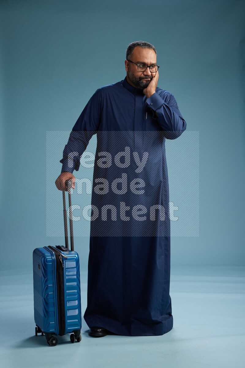 Saudi Man without shimag Standing pulling travel bag on blue background